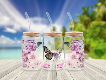 Drei 16 oz Glasbecher mit Bambusdeckel und Glastrinkhalm, verziert mit Blumenmotiven und Schmetterlingen in Rosa- und Lilatönen. Der mittlere Becher trägt die Aufschrift 'Blessed Mama' mit einem zentralen Schmetterling in Leopardenmuster, was eine feminin